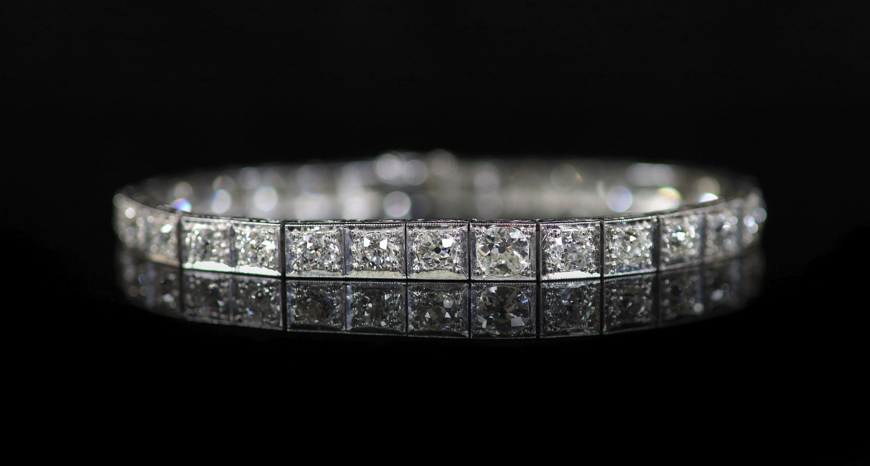 A mid 20th century engraved platinum and graduated old round cut diamond set line bracelet